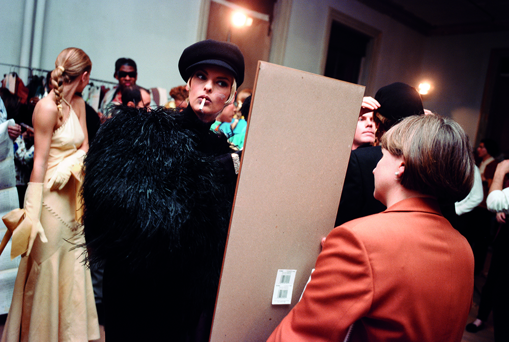 isaac mizrahi fashion, model backstage smoking a cigarette looking in a mirror