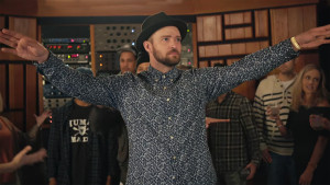 justin timberlake with arms up wearing a fedora and floral print shirt