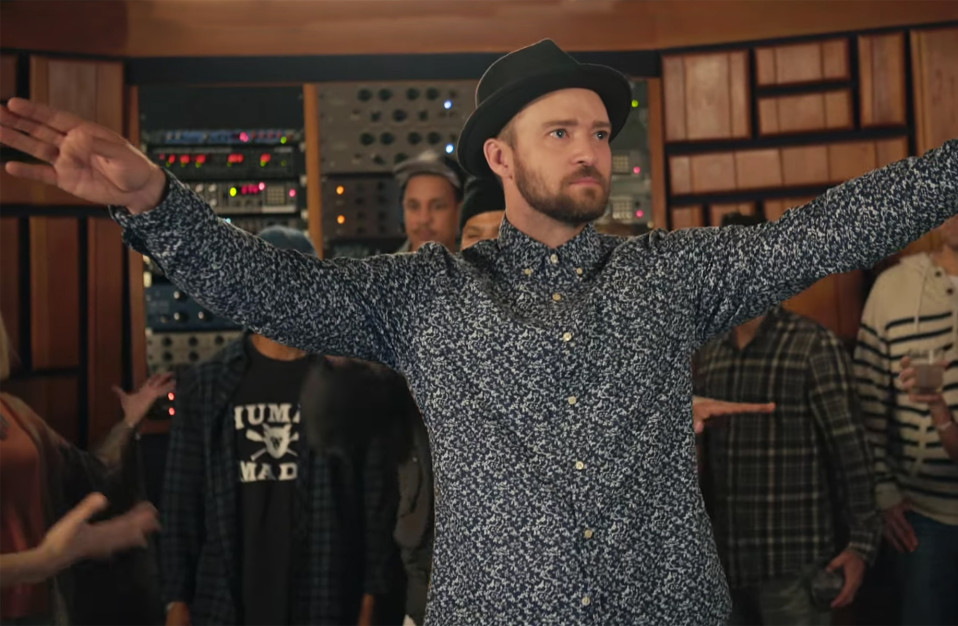 justin timberlake with arms up wearing a fedora and floral print shirt