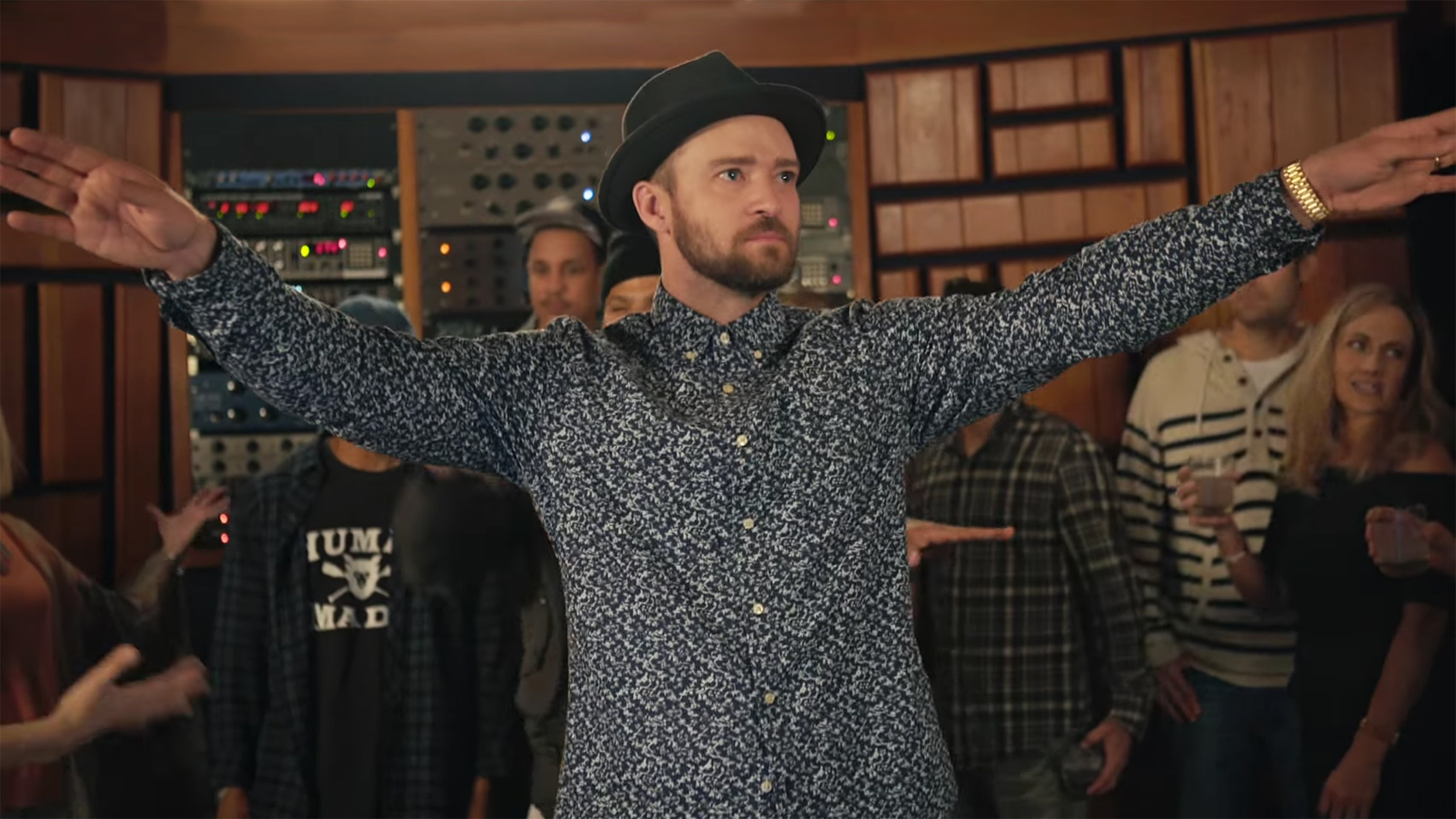 justin timberlake with arms up wearing a fedora and floral print shirt
