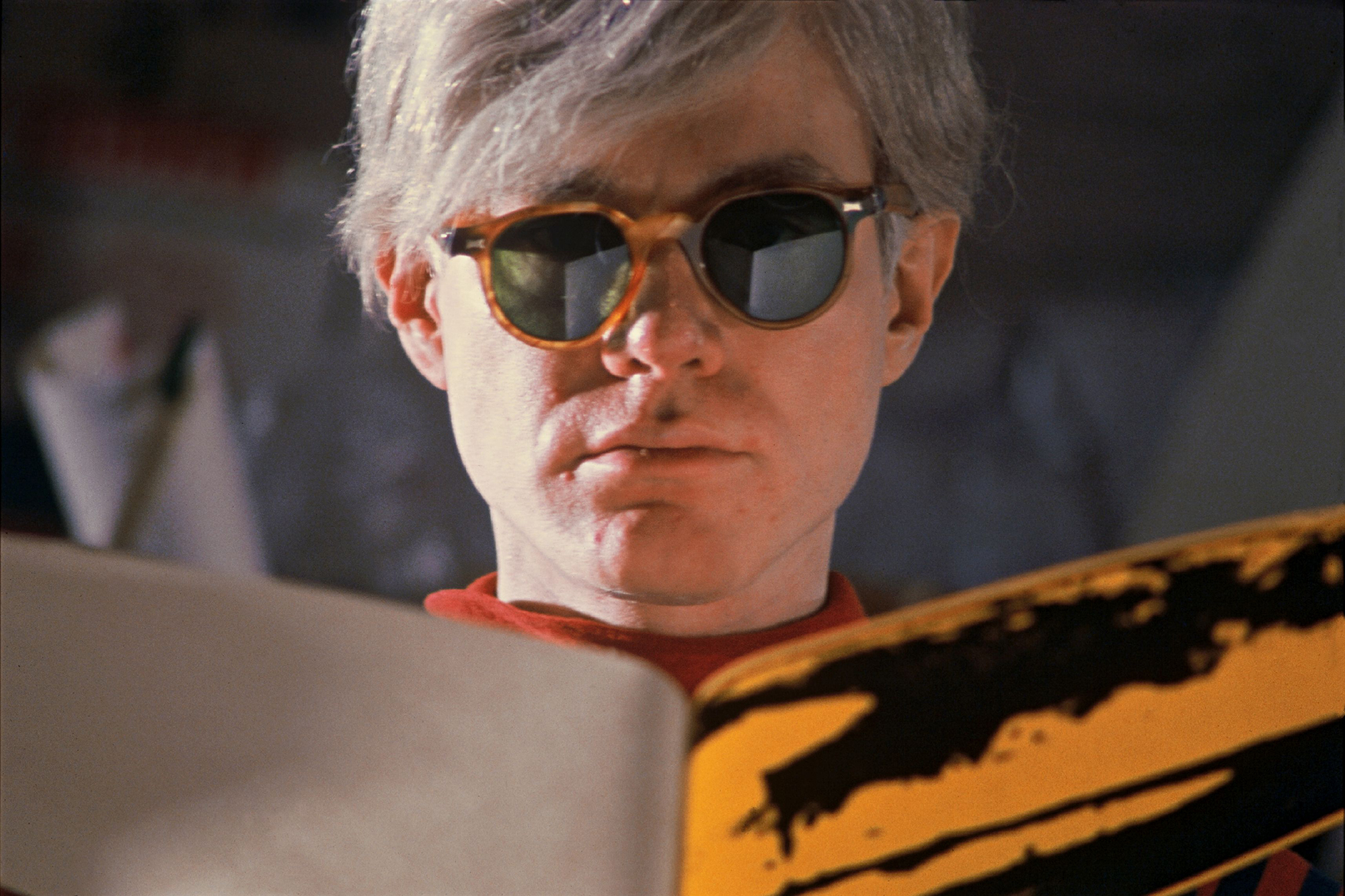 andy warhol wearing glasses and reading a book