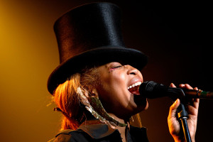 female performer singing into a microphone and wearing a top hat