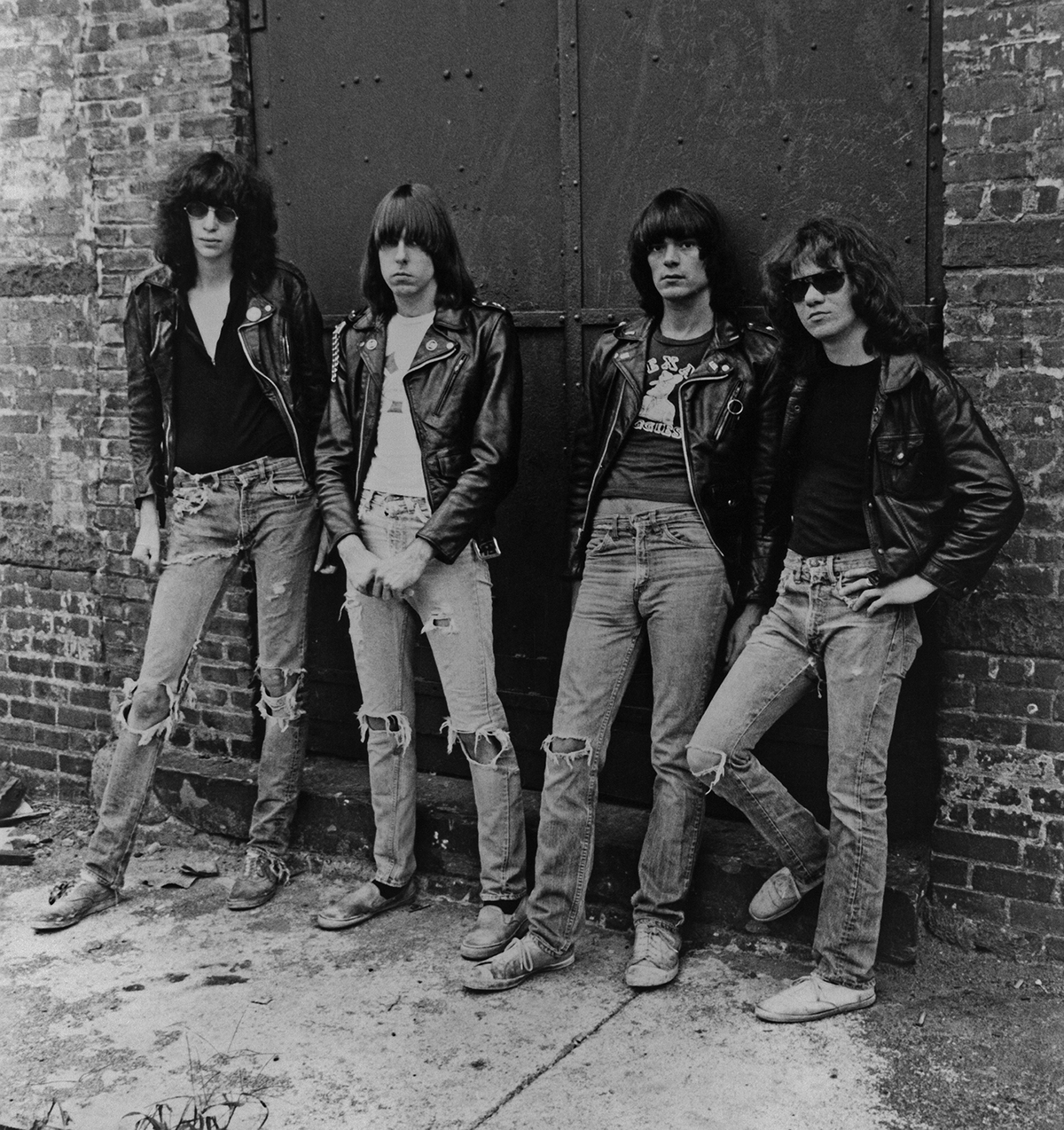black and white phot of the ramones leaning against brick building