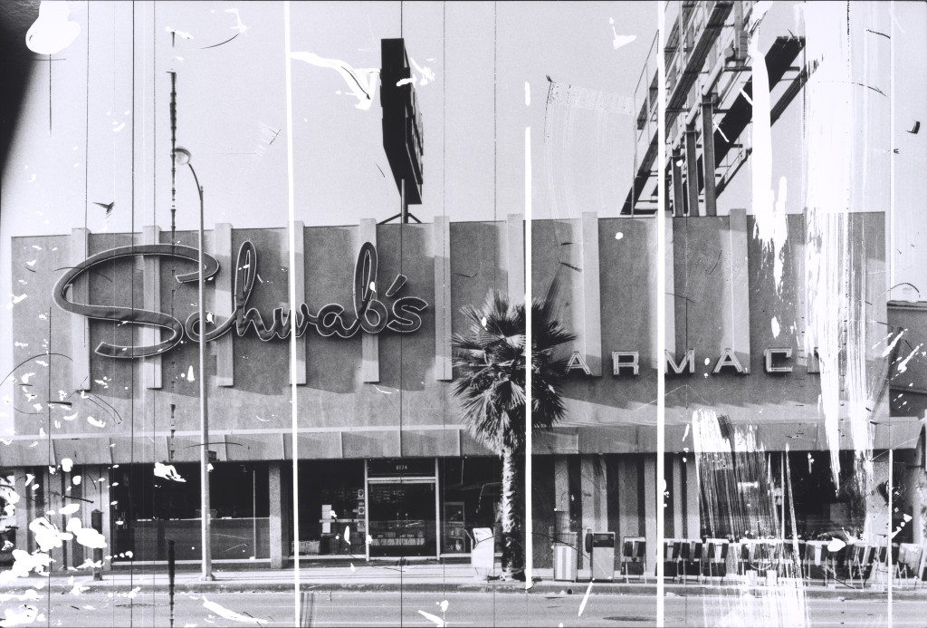 Schwab’s Pharmacy (1976), by Ed Ruscha, from the series The Sunset Strip (1995). Gelatin silver print from altered negative, 20 x 30 inches. Published by Patrick Painter Editions, Vancouver and Hong Kong. Fine Arts Museums of San Francisco. © Ed Ruscha.
