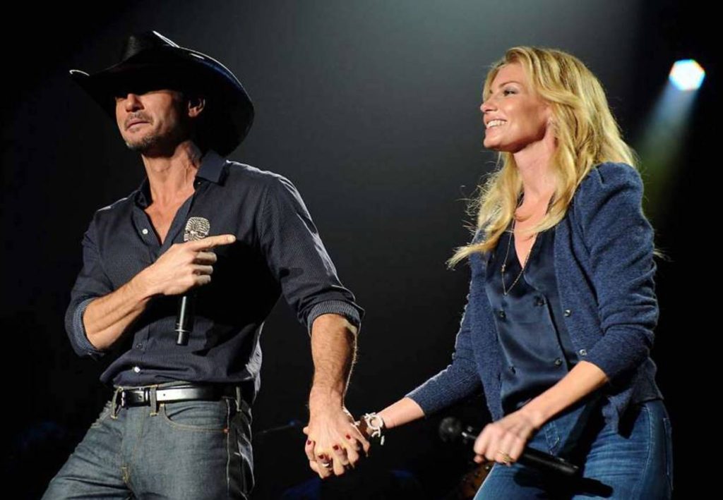 Tim Mcgraw and Faith Hill holding hands on stage