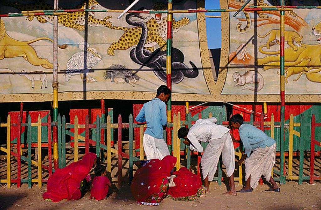 Photographer Rahubir Sing 4C bleed photograph of local villagers peeking outside a circus in Pushkar India, 1976 