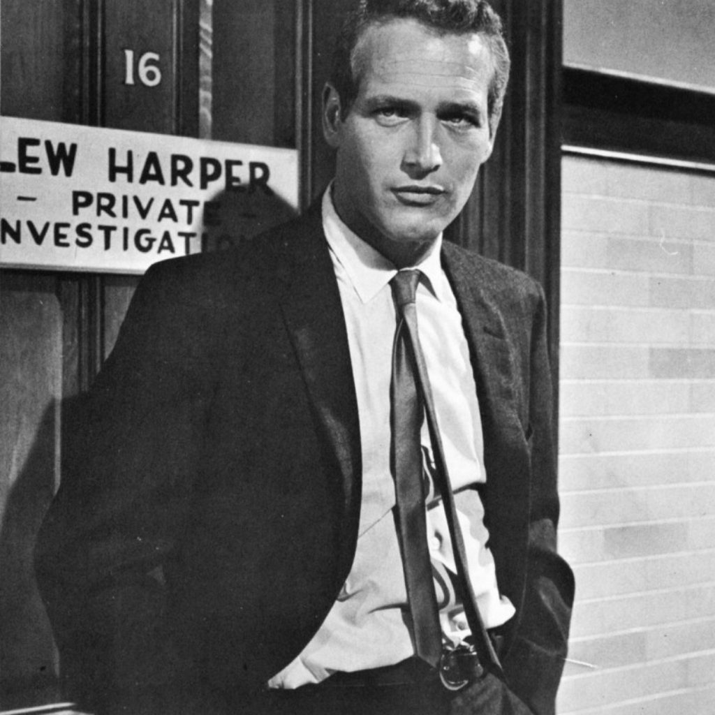 Actor Paul Newman in his twenties wearing a skinny tie and black suit
