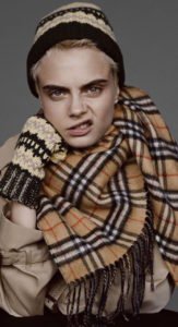 Cara Delevigne wearing a burberry scarf and snarling at the camera