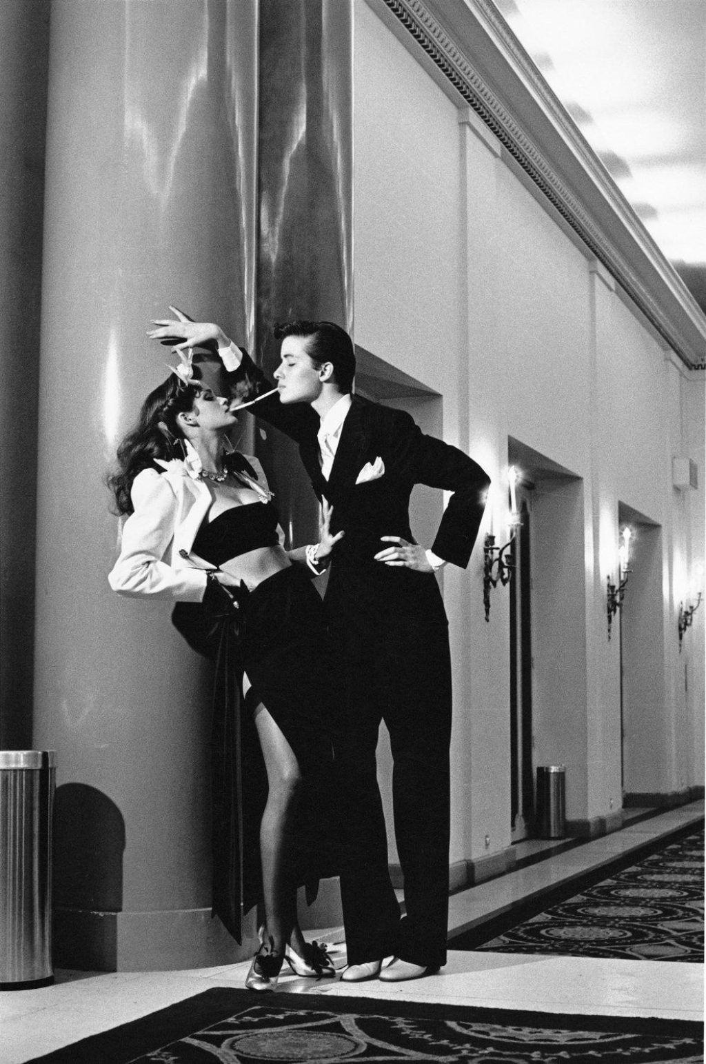Butch and femme in elevator lobby with cigarettes