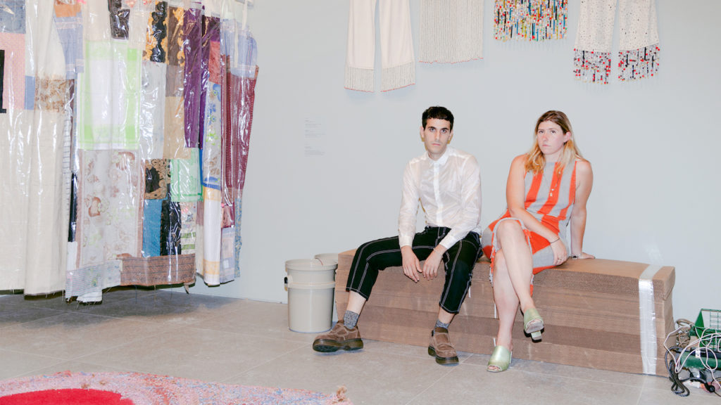 Photograph of Designers Mark Eckhaus and Zoe Latta sitting on a upholstered bench at the Whitney Museum of American Art