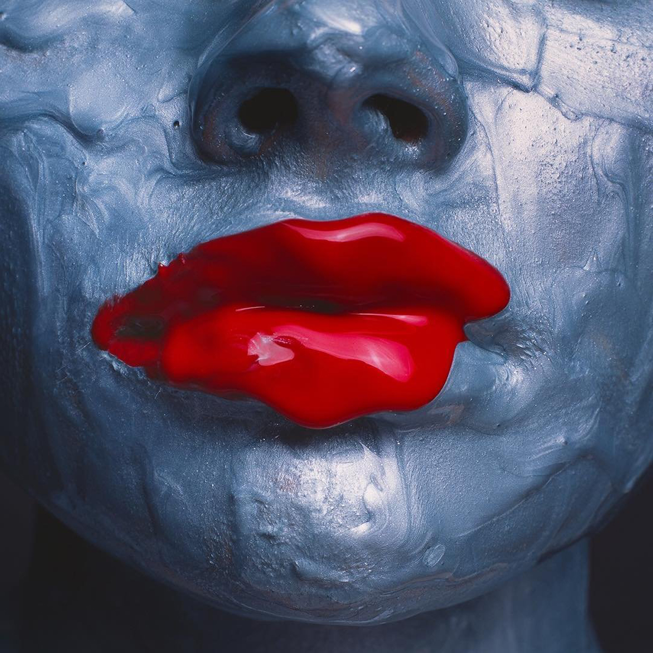 artistic image of woman with bright silver and red paint on her face