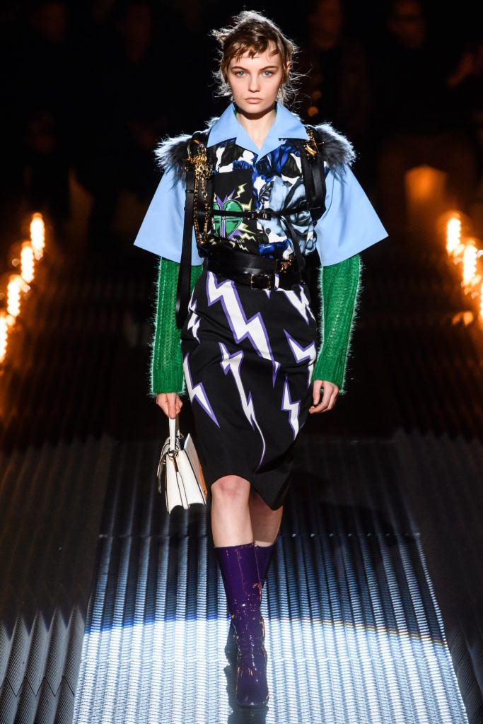 PRADA Mens 2019 Frankenstein Collection Runway Show in Milan Featuring Female Model Wearing Black Pencil Skirt with White and purple lined thunderbolts and purple patent leather boots