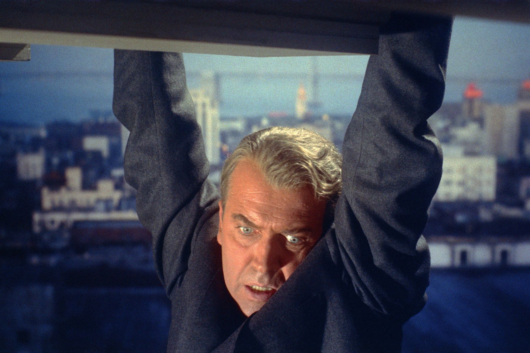 man clinging to a building ledge, about to fall