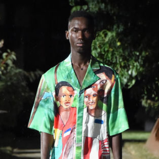 Pyer Moss Runway Model Wearing a green top and bottom printed with African faces of a boy and a man