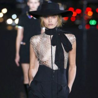 sexiest-womenswear designer of the year-YSL-2019-photo of runway model wearing hat, see through top, high waisted pants, long bow and lizard skin boots