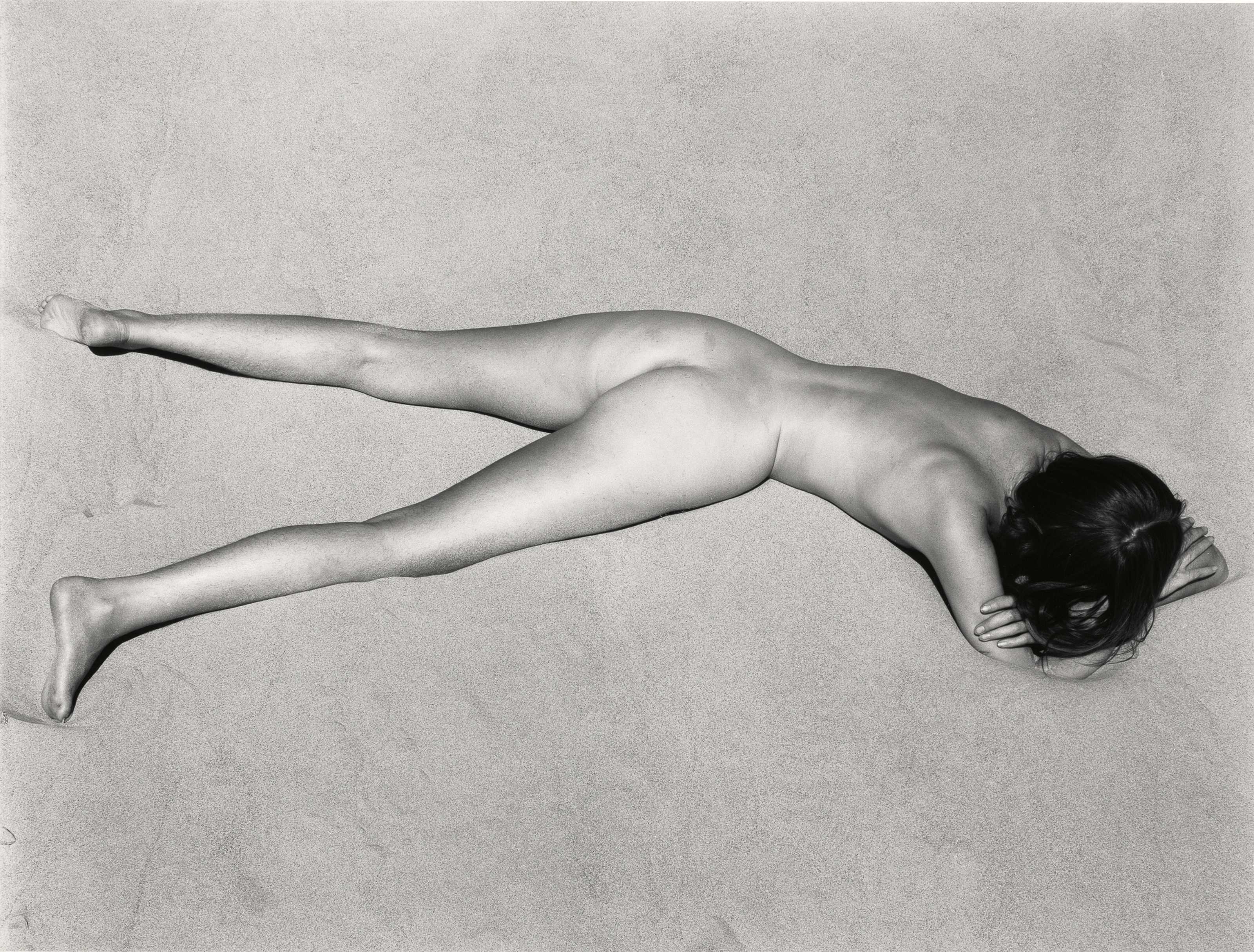 nude woman laying face down on the beach in California