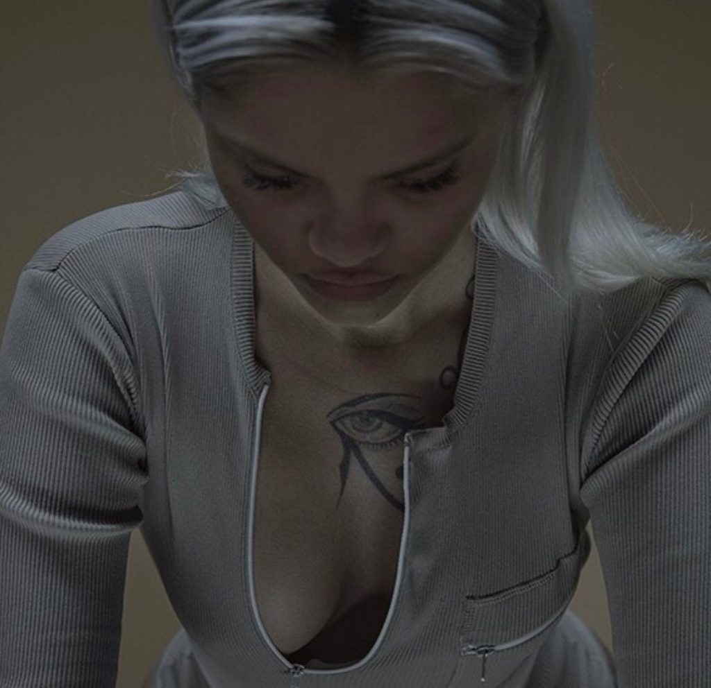 Platinum Blonde Model Wearing Kayne West Yeezy Sexy Beige un zipped showing a glimpse of her breast and tatoo