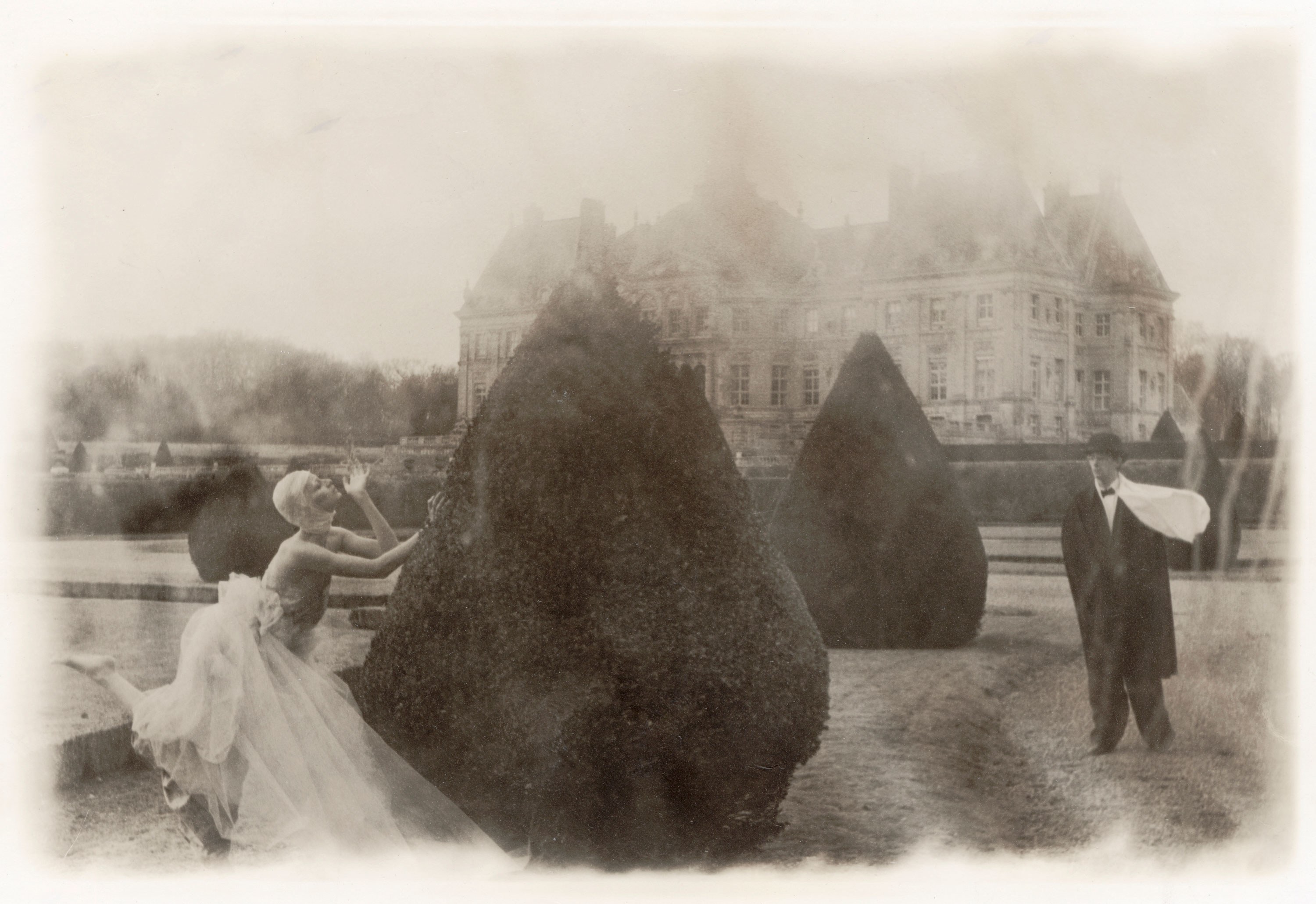 woman in a gown plays hide and seek in a topiary garden