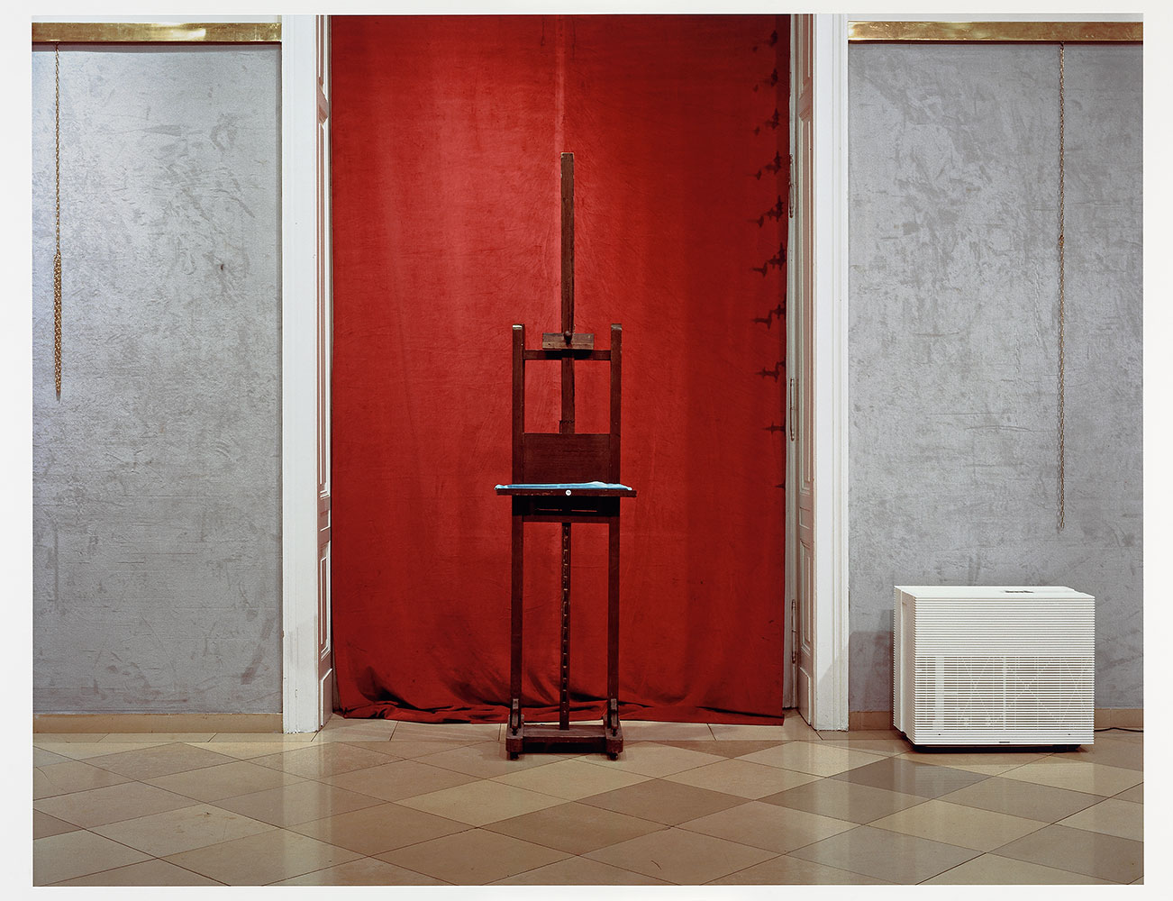 Lynne Cohen photograph of an empty easel in front of a red dropcloth