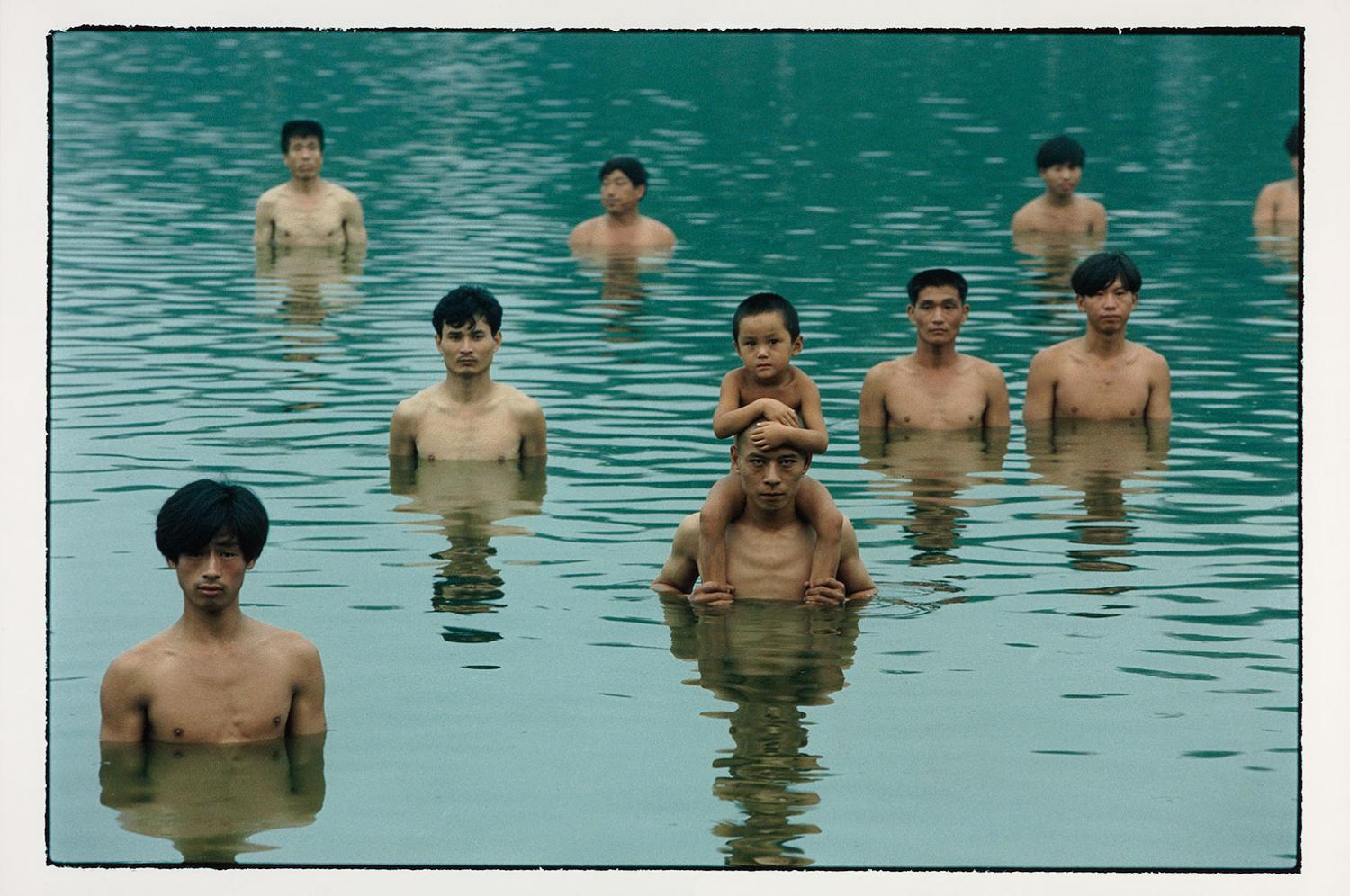 Zhang Huan photograph of women in a fish pond, one with a toddler on his shoulders