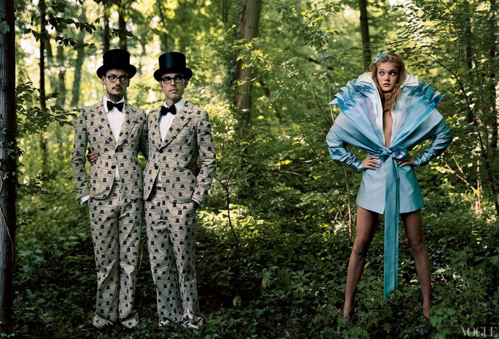 two men in matching suits and model in a blue dress in a alison wonderland fairy-tale-2003-12-annie-leibovitz-1_173842804075