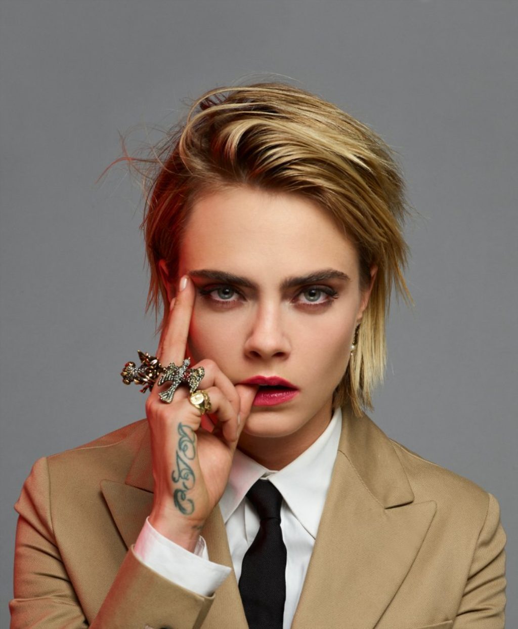 Super model Cara Delevingne in a Dior khaki suit white shirt and black tie