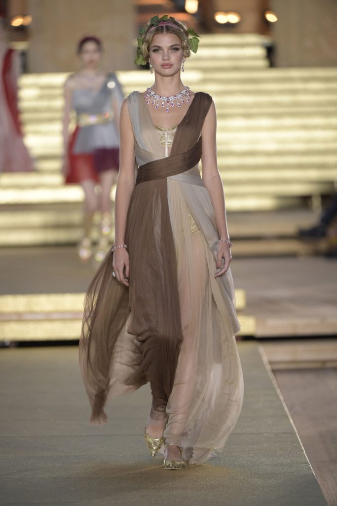 Dolce & Gabbana Runway Show 2019 Model Wearing Brown and Beige Draped Roman Dress, Amazing Pink and Platinum Necklace and Head Dress