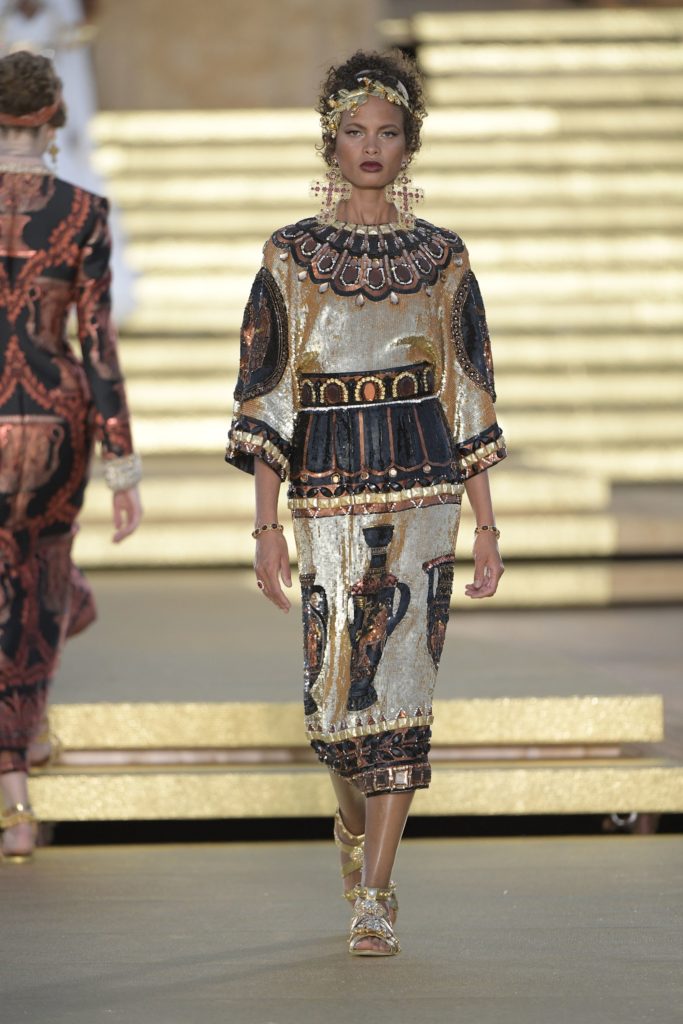 Dolce & Gabbana Runway Show Spring 2019 Model Wearing Gold Leaf Roman Head Dress Oversized Gold Cross Earings and Bejeweled Black and White Dress 