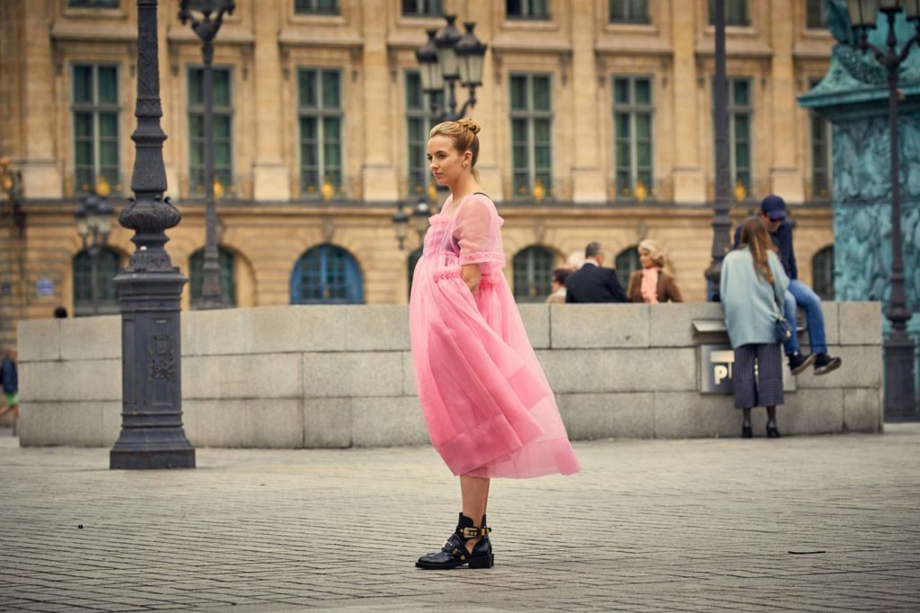 Vilanelle wearing pink dress and black buckle boots in Killing Eve