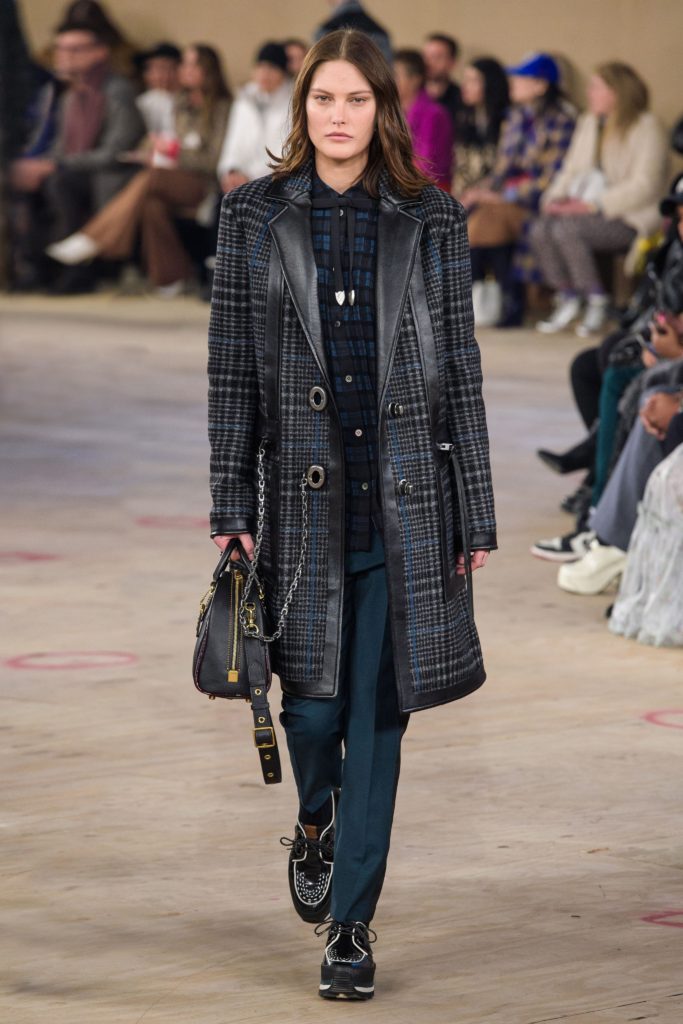 COACH Runway Fall 2019 Model Wearing Black and Blue Plaid Coat with Leather Trim, thin black bow tie_plaid shirt_blue pants and black sneakers with white trim