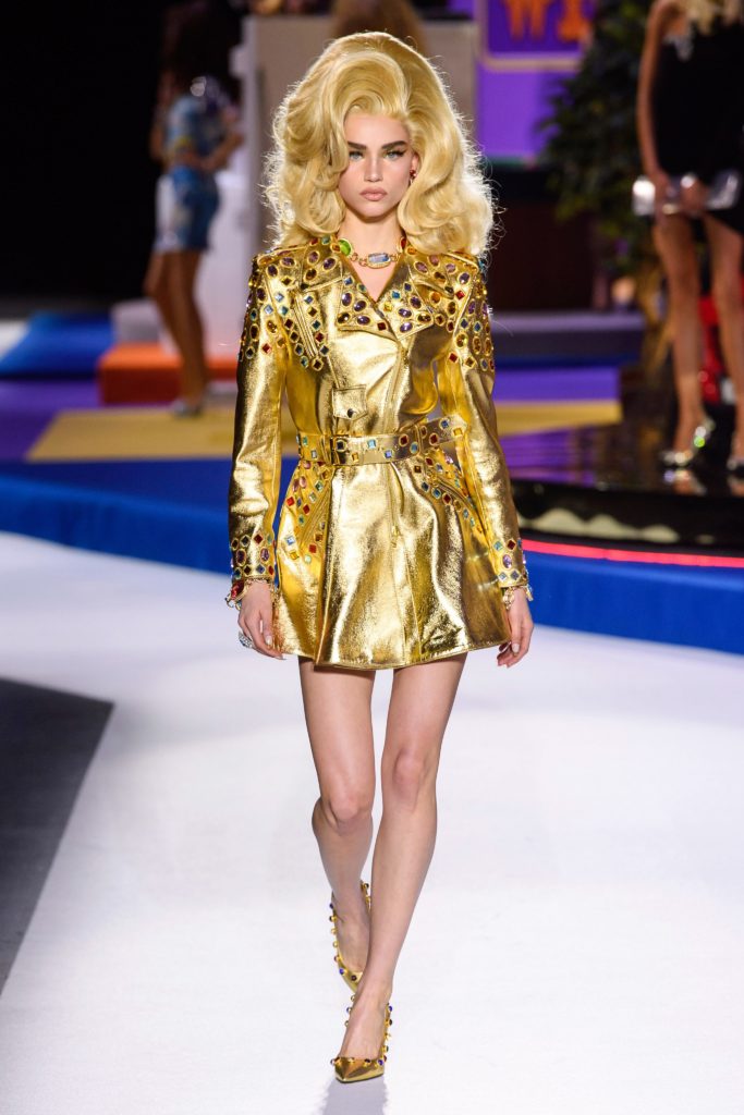 MOSCHINO Fall 2019 Runway Model in Blonde Big Hair Do and Gold Leather Belted and Sequined Mini Dress