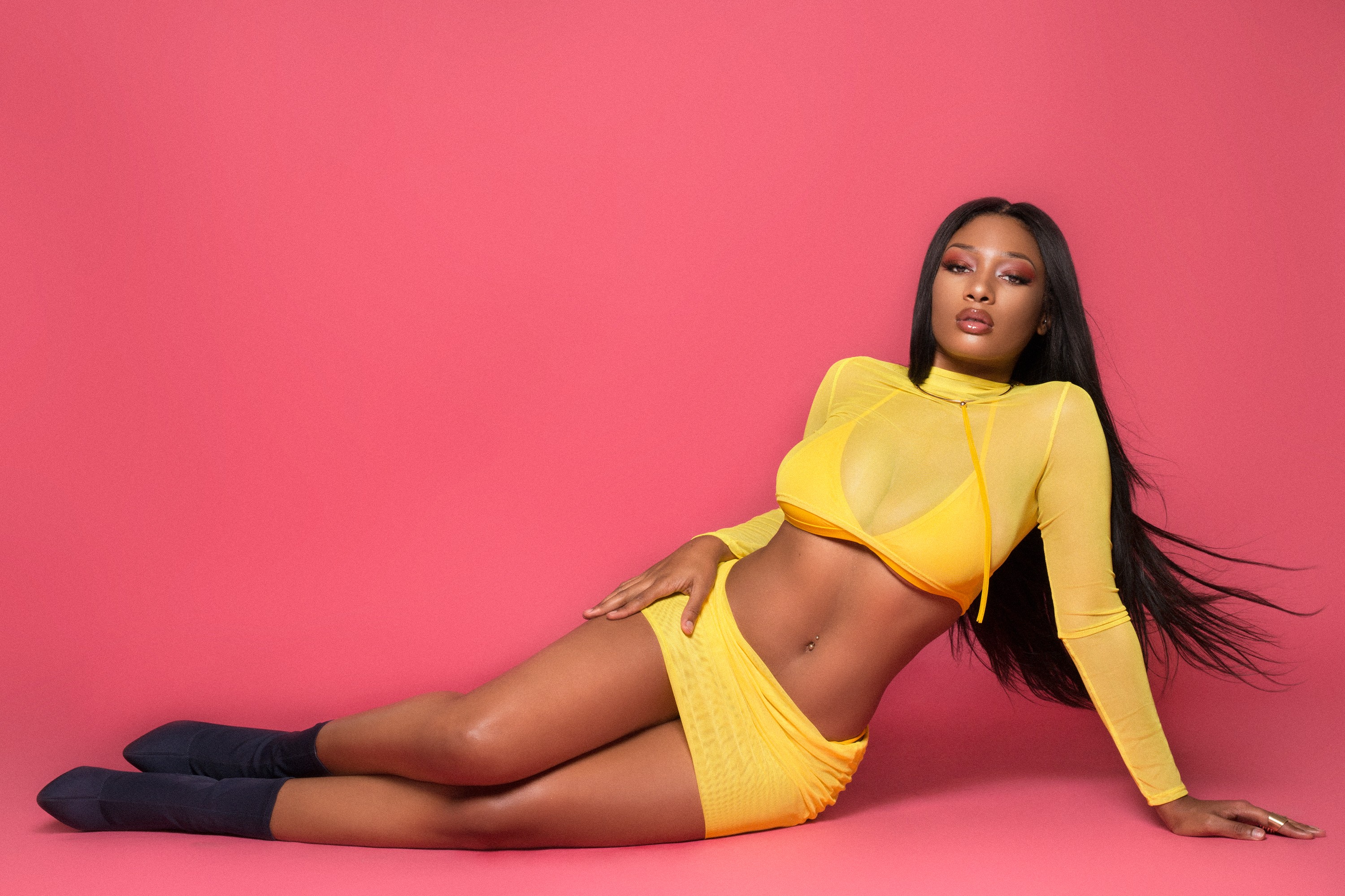 Megan Thee Stallion in a provocative pose wearing sexy yellow see through top and mini dress