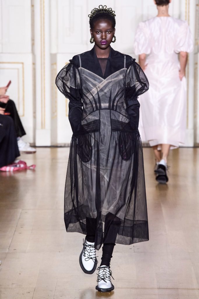SIMONE ROCHA Fall 2019 Runway Model Wearing Crown_sheer black dress with puffy short sleeves and white shoes with black rubber soles and laces
