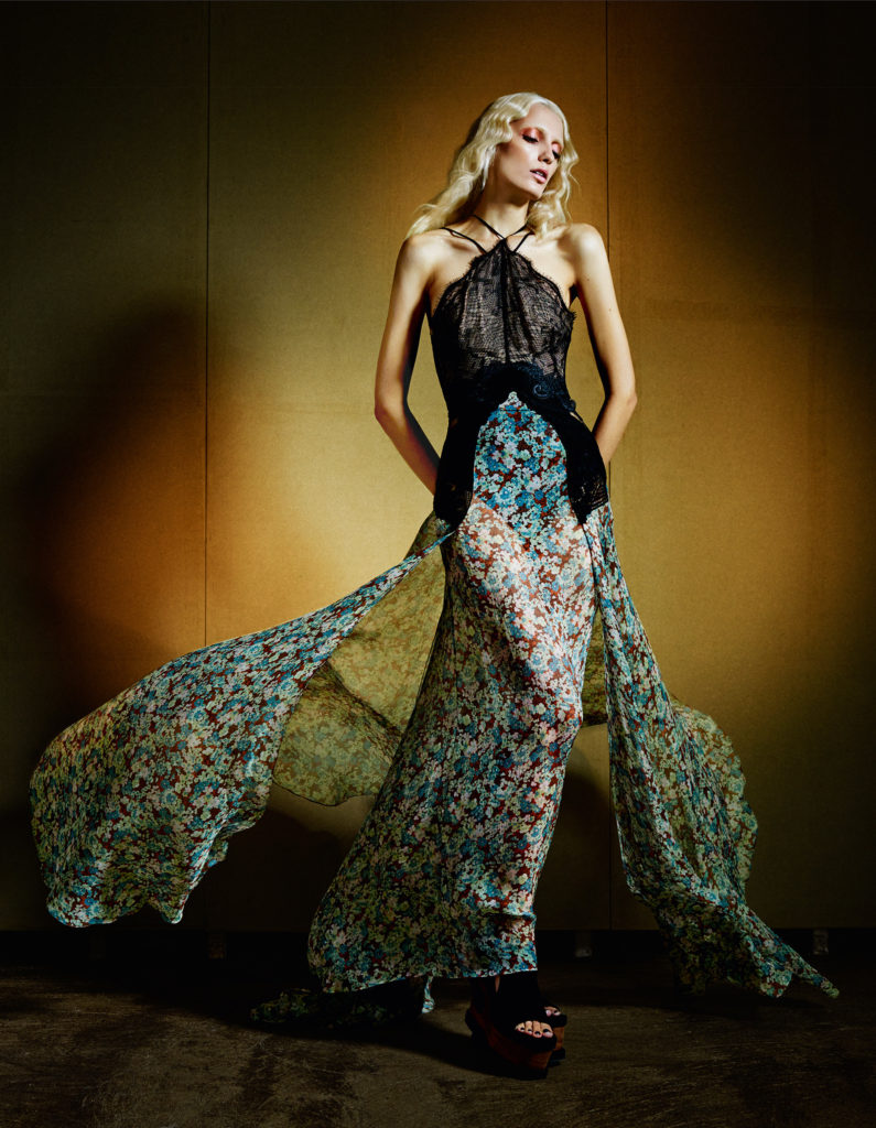 Stella McCartney Model wearing Recyled Black Sheer Halter over a flowing Green Floral Print Long Dress