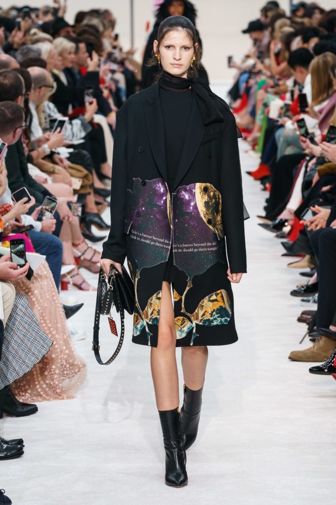 VALENTINO Fall 2019 Runway Model Wearing Black Neck Scarf and Black Coat with Interesting Abstract Image on the botton of the coat and black pointed toe boots