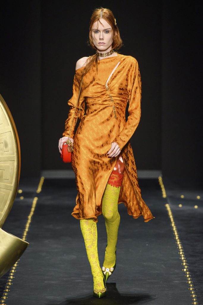 VERSACE Fall 2019 Runway Model wearing Versace greek key pattern gold choker_orange silk patterned dress and lime green floral stockings and matching lime green shoes