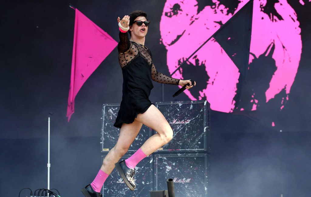Yungblud on stage wearing a black negligee-black see through polka dot shirt-hot pink socks and shades