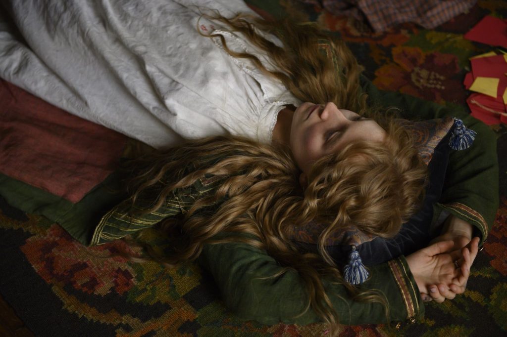 saoirse ronan as Jo Marsh in Little Women lying on her back with her beautiful long hair looking up in the sky and wearing a white dress and green jacket with striped gold sleeves