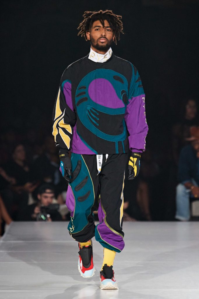 Reebok by Pyer Moss Runway SS 2020 Model wearing dreds-ornate turquois, purple and yellow printed top and matching bottoms