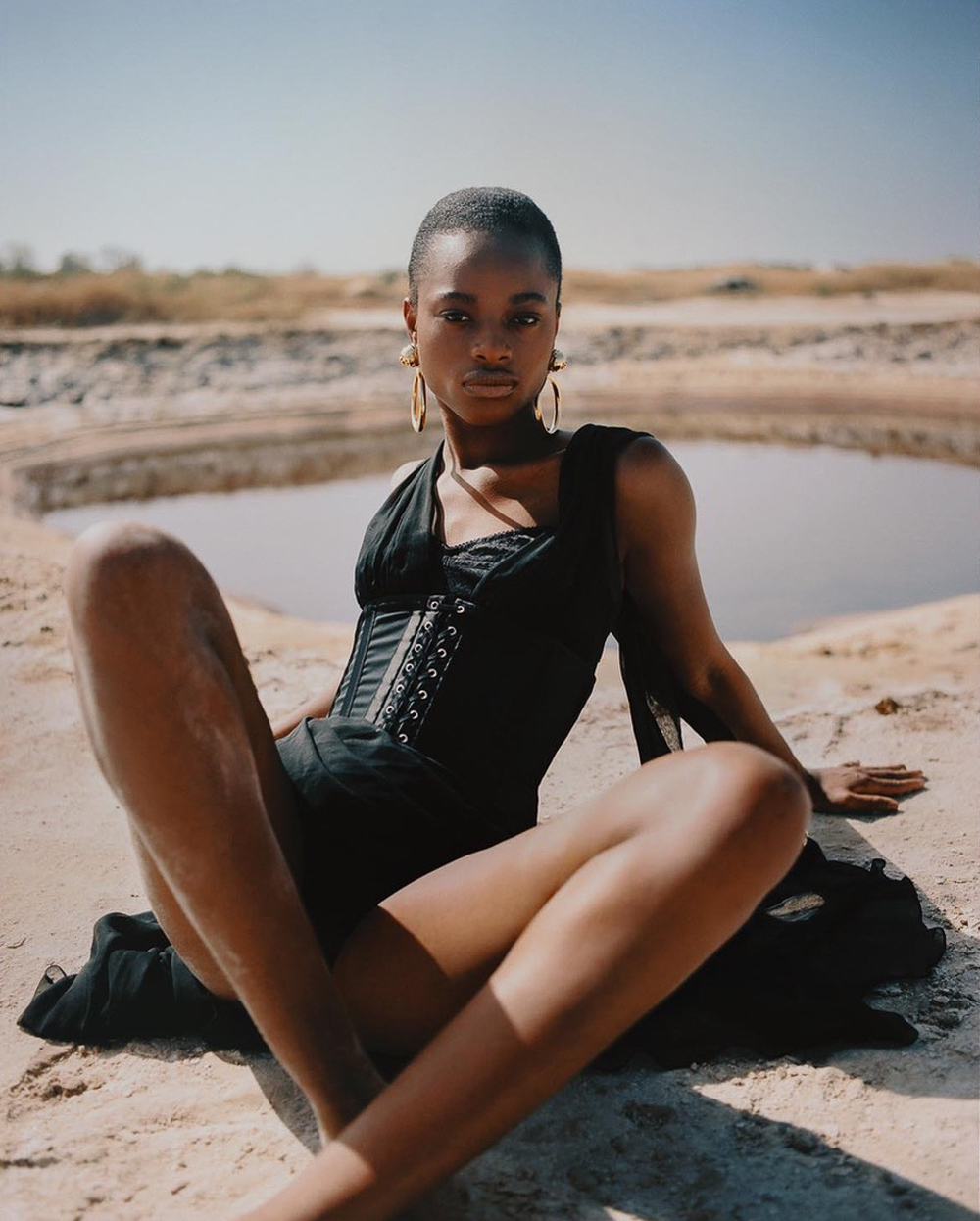 Model-Mayowa-Nicholas-Wearing-Huge-Gold-Hoop-Earings-Sitting-on-a-Beach