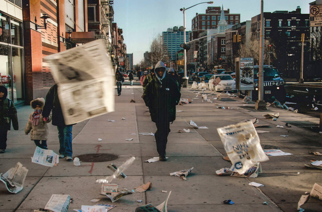 BLOWN HEADLINES: High winds blow loose newspaper pages around 125th street in Harlem near the IRT subway entrance as some people make their way to work that morning, 2006 shot by Ozier Muhammad