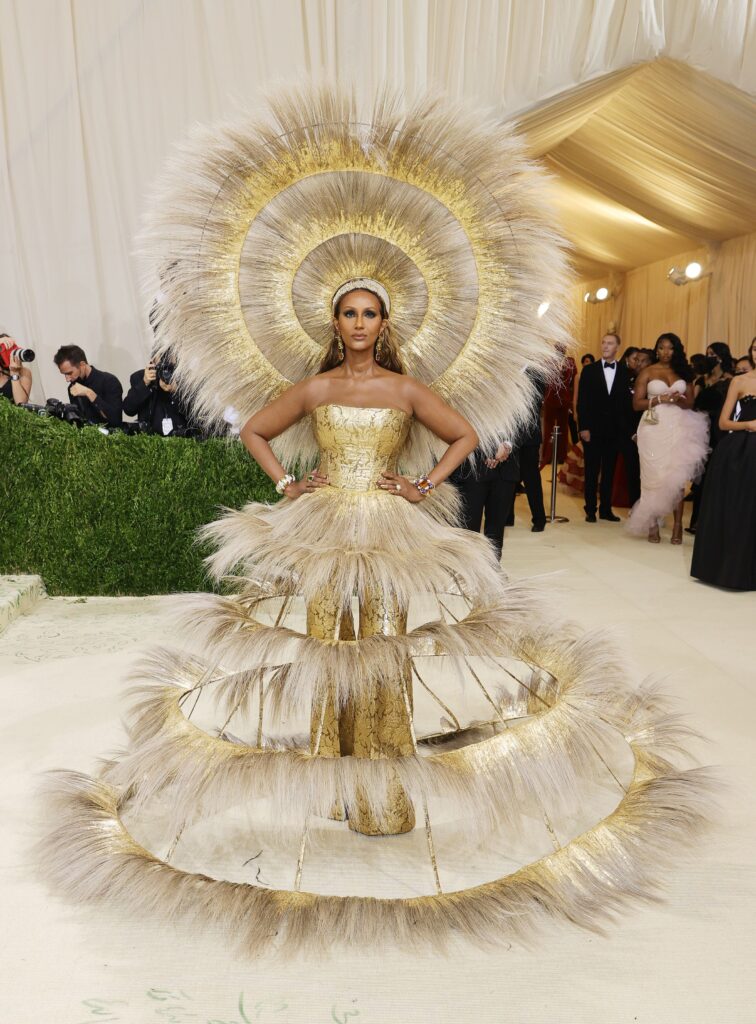 Supermodel Iman wearing over the top gold dress and head piece by Harris Reed Met Gala 2021