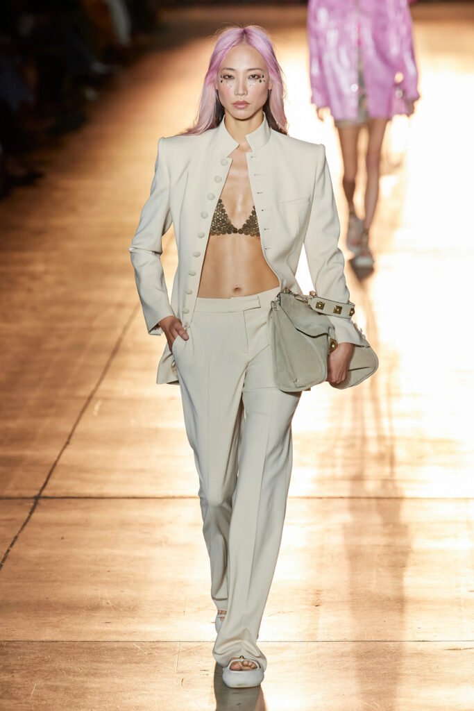 ETRO RUNWAY SPRING SUMMER 2022 MODEL WEARING PINK HAIR, BEIGE SUIT AND GOLD BRASSIERE