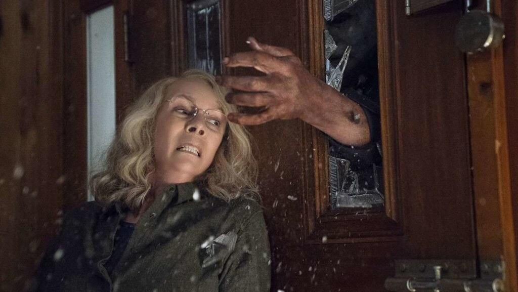 Jamie Lee Curtis as Alison strode fearing for her life as the Killer punches his arm throught the glass front door to attack her