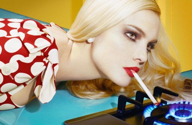 Miles Aldridge Image of Woman Lighting Her Cigarette on a stove burner flame