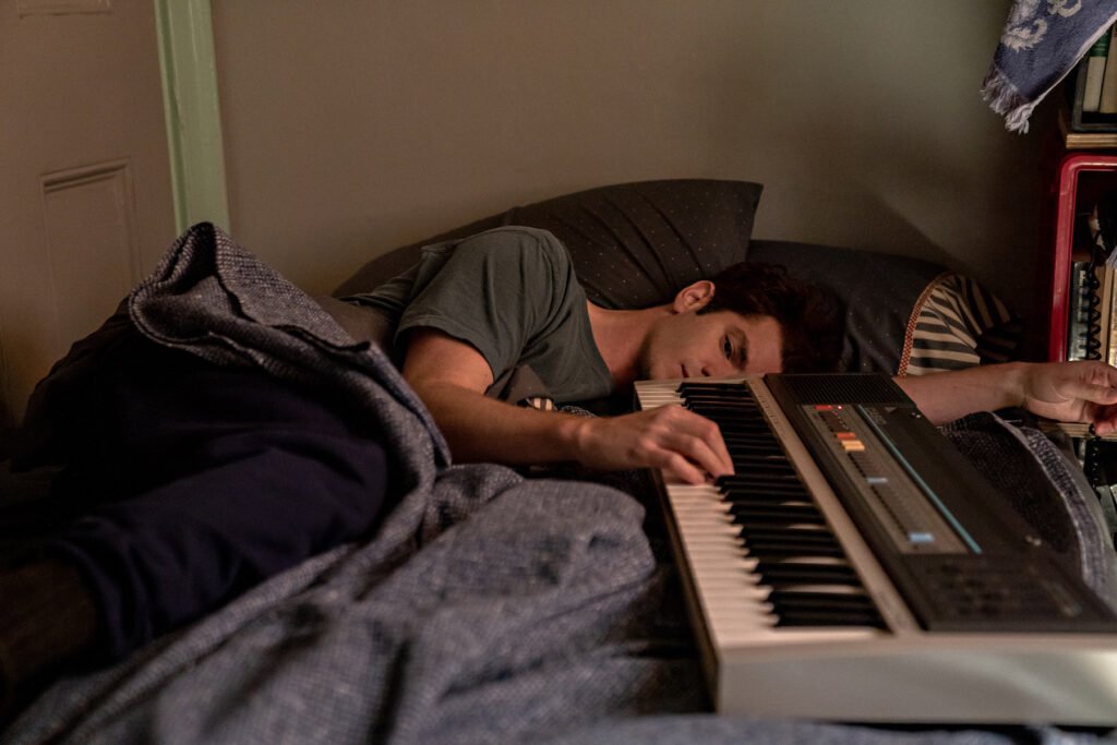 Andrew Garfield half asleep with hand resting on keyboard in Tick Tick Boom