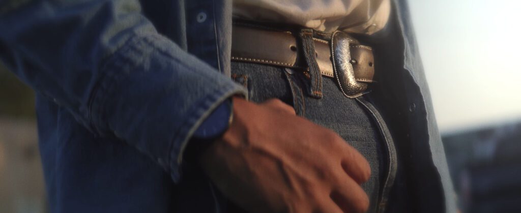 Into The Circle Image of a Dakota Natvie American View of His Belt and Thumb in his Jeans Pocket