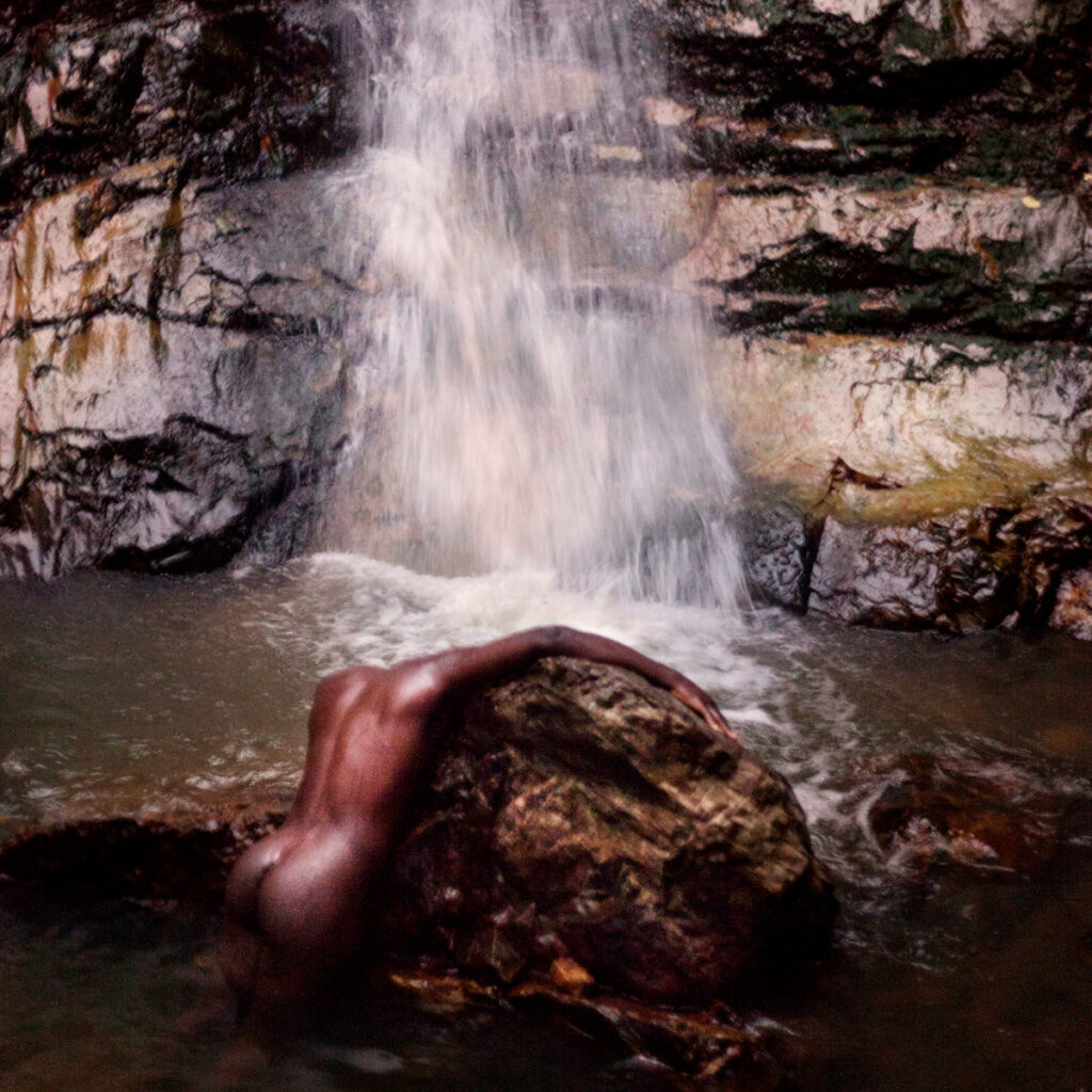 Moses Sumney Naked Against a Rock in A Waterfall