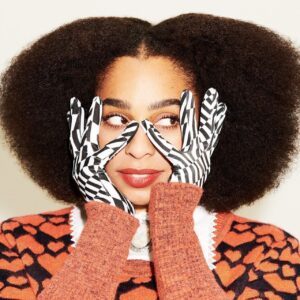 Celeste with graphic pattern gloves touching the sides of her face