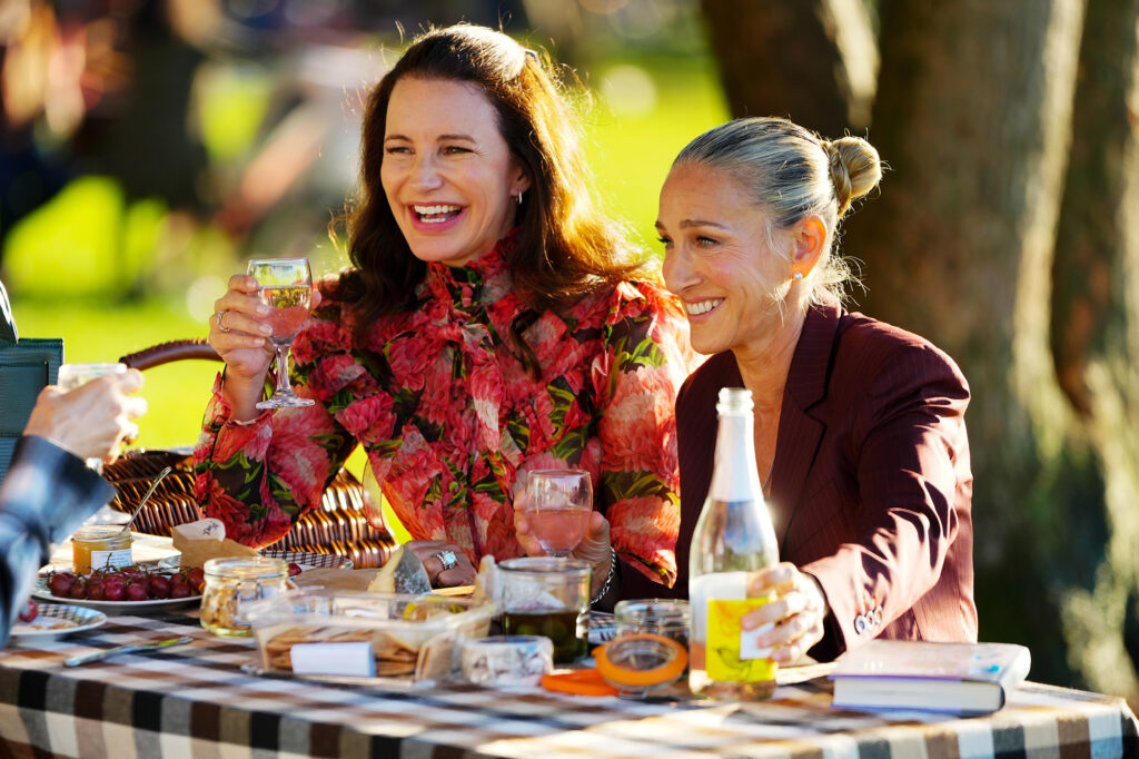 Charlotte-and-Carrie-Toasting-Wine-Glasses-Sitting-Outside-at-a-Picnic-Table